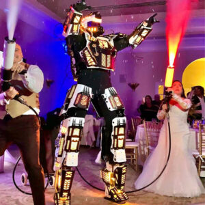 <b>Dancing LED Robots</b> (8.5Ft Tall) $1,300 plus $100 Travel expenses . Additional: Custom logo on chest + $100 Package included 40 minutes interactive session includes greetings, get-together activities, dancing, and taking pictures). Take your wedding to the next level with Dancing LED Transformer Robots—the ultimate showstopper! These high-tech robots light up the dance floor with vibrant LED displays and perform jaw-dropping dance moves, creating an electrifying atmosphere your guests will never forget. Perfect for a high-energy entrance, special moments, or simply entertaining your guests, these robots add a futuristic, fun twist that’s sure to have everyone talking long after the celebration ends!